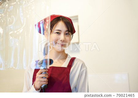 A clerk standing in a store with a vinyl partition 70021465