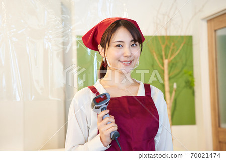 A clerk standing in a store with a vinyl partition 70021474