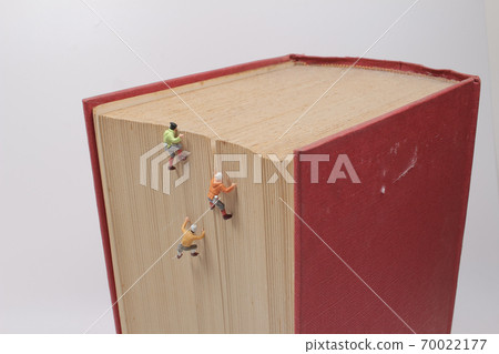 a mini of figures climb, conquer a big book. a mini of figures climb, conquer a big book. 70022177