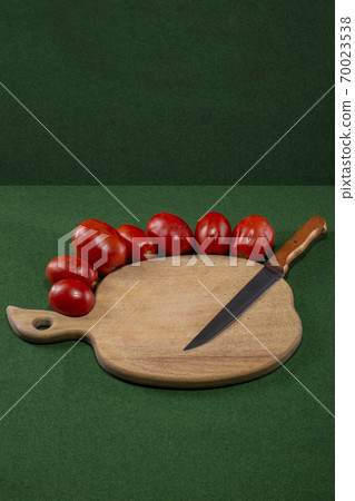 Ripe red tomatoes with a knife and a cutting wooden board Ripe red tomatoes with a knife and a cutting wooden board 70023538