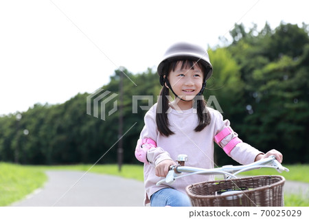 Girl practicing by taking training wheels on a bicycle 70025029