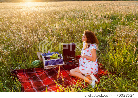 A pregnant woman having a picnic in the wheat field 70028524
