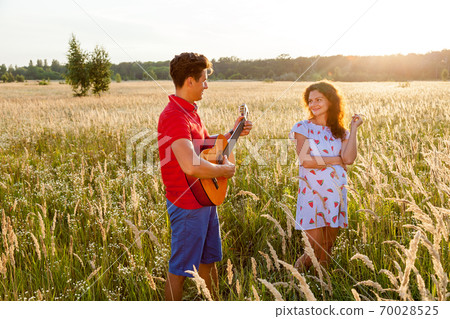 A man is playing the guitar for his woman A man is playing the guitar for his woman 70028525