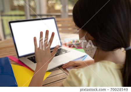 Girl wearing face mask using laptop at home Girl wearing face mask using laptop at home 70028549