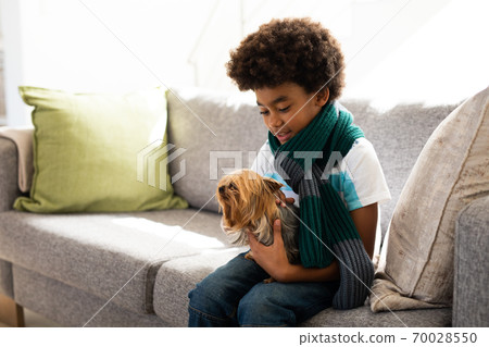 Young boy holding his puppy dog at home 70028550