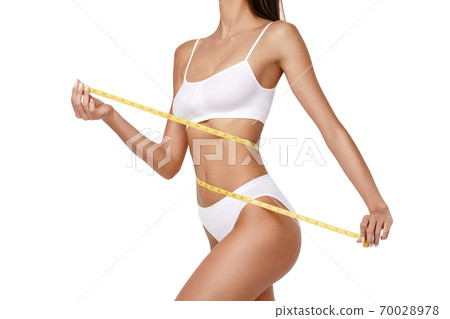 Slim tanned woman's body over gray background - waist measurement 70028978