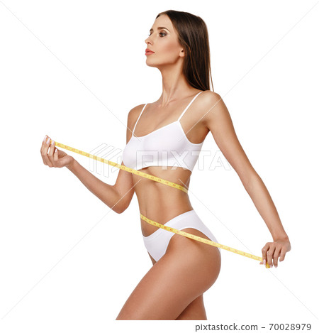 Slim tanned woman's body over gray background - waist measurement 70028979