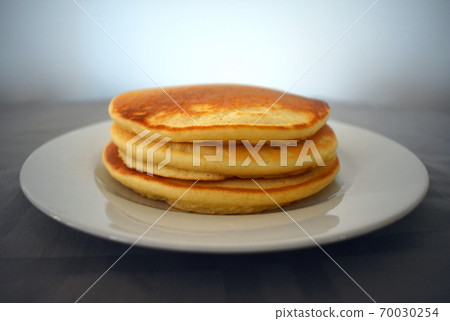 A stack of three pancakes on a plate 70030254