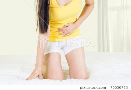 Young upset unhappy woman suffering from menstruation pain, PMS at home. Abdomen and stomach pain during criticals days. Health problems 70030753