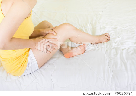 woman holding the legs with pain on bed,health care and medical concept 70030784
