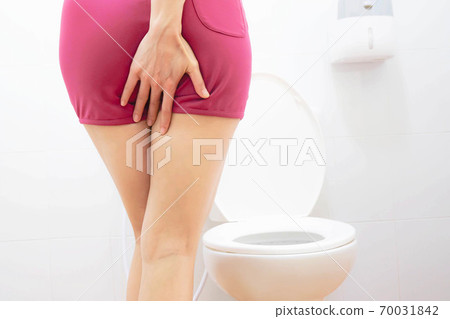 Women wearing white sleepwear, Sitting on the toilet Hand holding the stomach,standing in the toilet, Holding a toilet paper, bent, stomachache health care concept 70031842
