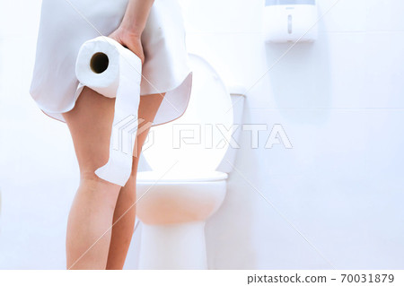 Women wearing white sleepwear, Sitting on the toilet Hand holding the stomach,standing in the toilet, Holding a toilet paper, bent, stomachache health care concept 70031879