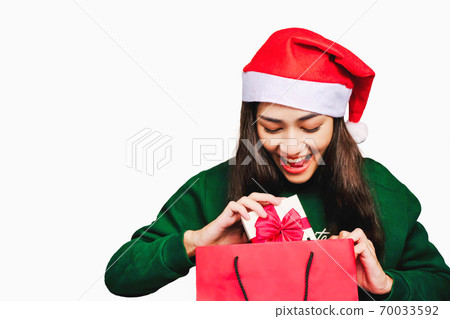 Selective focus Young beautiful asian woman wore green sweater and santa hat,Excited, surprised and happy, Holding a gift box with a bow isolated on white background,Christmas day and New Year's gifts Selective focus Young beautiful asian woman wore green sweater and santa hat,Excited, surprised and happy, Holding a gift box with a bow isolated on white background,Christmas day and New Year's gifts 70033592