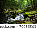 A river flowing through a mountain surrounded by greenery 70036503