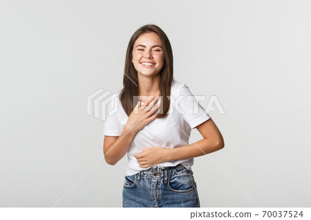 Happy beautiful girl laughing and touching chest, looking thankful 70037524