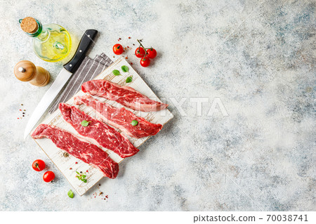 Raw steak with spices on wooden cutting board Raw steak with spices on wooden cutting board 70038741