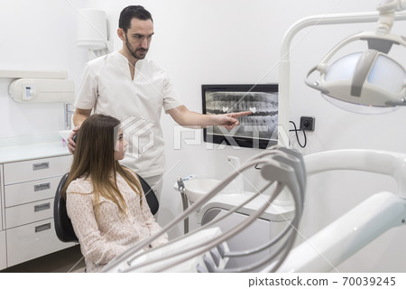 Attractive young dentist showing to his patient 70039245