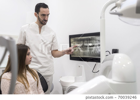 Attractive young dentist showing to his patient 70039246