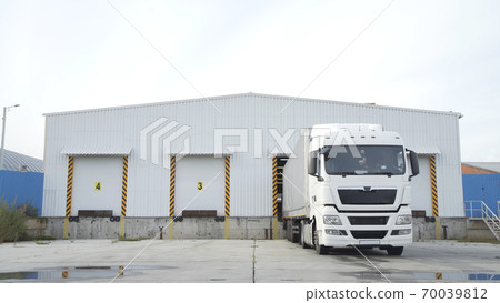 Semi-trailer truck standing at warehouse ramps for load or unload goods at dock logistics park. Truck in parking near warehouse. 70039812