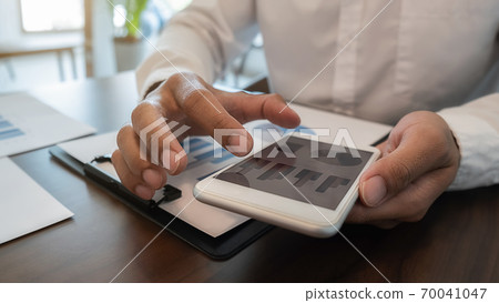 Businessman using smartphone to checking the company performance chart in the office. 70041047
