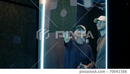 Male shooters examining target together 70041386