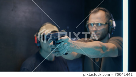 Mature instructor teaching man to shoot pistol 70041441