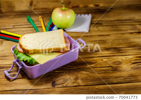 Back to school concept. School supplies, apple and lunch box with sandwiches on a wooden desk 70041773