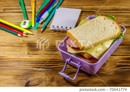 Back to school concept. School supplies and lunch box with sandwiches on a wooden desk 70041774