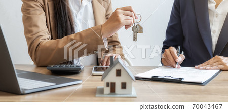 state agent holding a key and asking costumer for contract to buy, get insurance or loan estate. state agent holding a key and asking costumer for contract to buy, get insurance or loan estate. 70043467