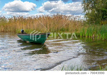Plastic fishing boat with motor on the lake in summer day Plastic fishing boat with motor on the lake in summer day 70043990