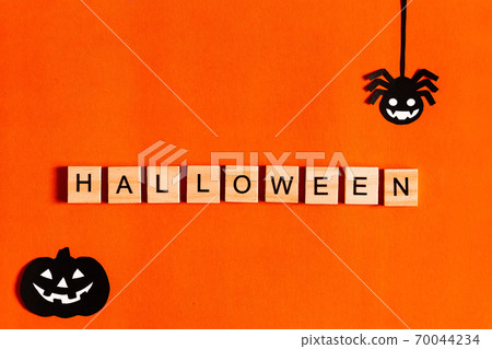 Halloween lettering on orange background with black paper silhouettes, bats, pumpkin, spider. The 70044234
