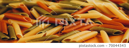 Frame made of colorful green, yellow and red penne pasta naturally coloured with tomato and spinach. 70044343