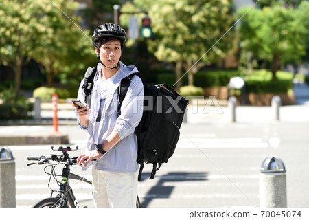 Delivery man delivering by bicycle with a smartphone Delivery man delivering by bicycle with a smartphone 70045074