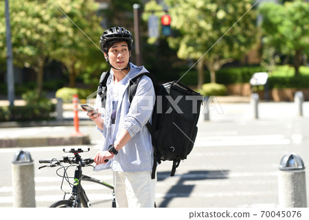 Delivery man delivering by bicycle with a smartphone Delivery man delivering by bicycle with a smartphone 70045076