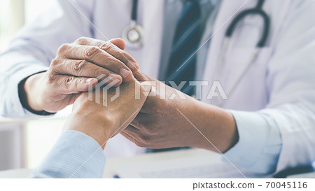 Patient listening intently to a male doctor explaining patient symptoms or asking a question as they discuss paperwork together in a consultation 70045116