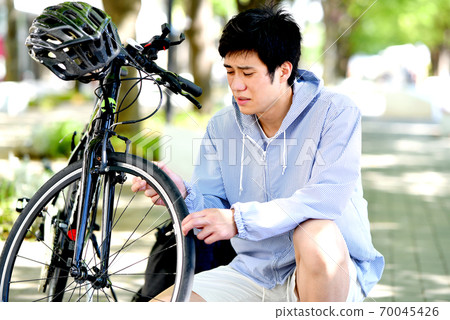 A young man in trouble with a bicycle A young man in trouble with a bicycle 70045426