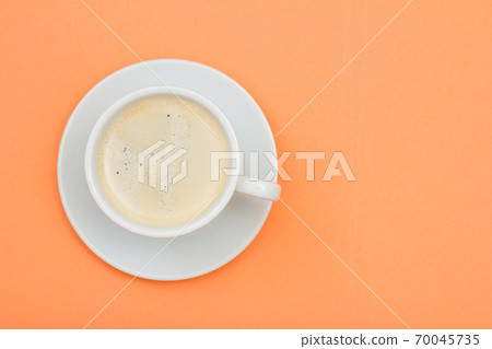 White porcelain cup of black coffee on saucer on peach color background White porcelain cup of black coffee on saucer on peach color background 70045735