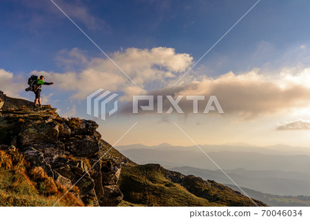 A little boy standing on a large rocky rock admires the landscape of the Carpathians, the top of Mount Pip Ivan Chornohirsky. A little boy standing on a large rocky rock admires the landscape of the Carpathians, the top of Mount Pip Ivan Chornohirsky. 70046034