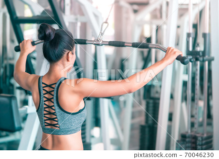 Asian woman is working out her back rear muscle by pulling weight in fitness sport gym. Asian woman is working out her back rear muscle by pulling weight in fitness sport gym. 70046230