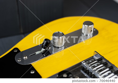 Volume, tone and switcher controls of a classic yellow and black electric guitar 70046440