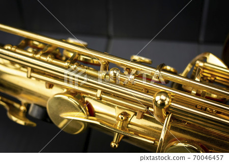 Keys and rods of a golden and shiny saxophone, in the foreground, on gray wooden background Keys and rods of a golden and shiny saxophone, in the foreground, on gray wooden background 70046457