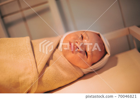 A newborn baby wrapped up after birth lies on the table A newborn baby wrapped up after birth lies on the table 70046821