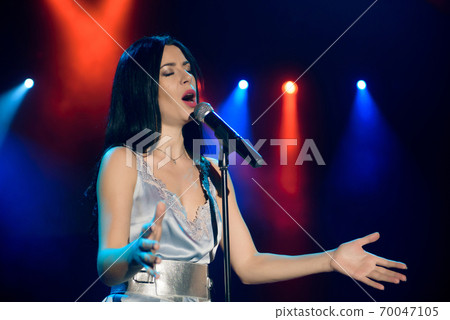 Singer with microphone on the colorful light stage background 70047105
