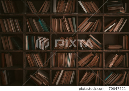 Paper books on wooden bookshelves. Library concept. Abstract retro background or wallpaper. Tinted image. High quality photo 70047221