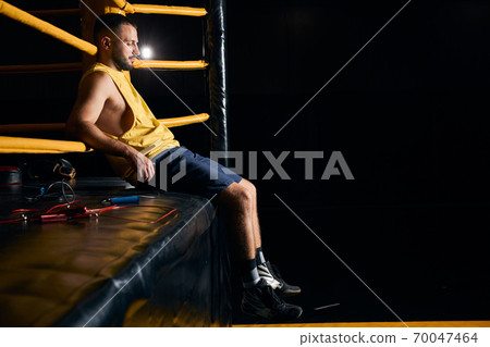 Tired boxer sitting on the side of the ring Tired boxer sitting on the side of the ring 70047464