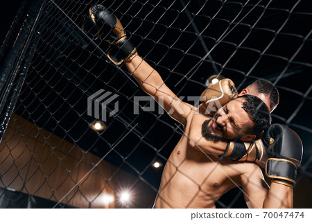 Struggling fighter in a clutch holding to the net 70047474