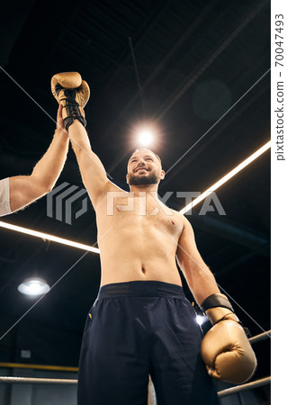 Pleased fighter standing in the ring raising his arm 70047493