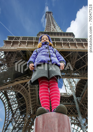 A girl against backdrop of the Eiffel Tower dressed in a blue jacket A girl against backdrop of the Eiffel Tower dressed in a blue jacket 70047528