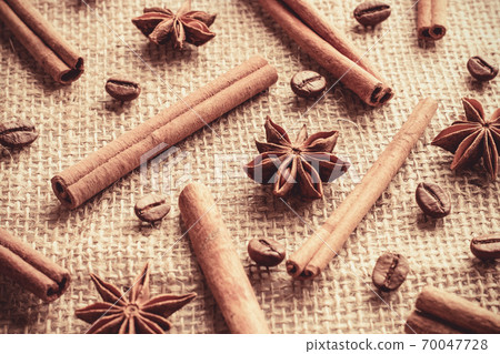 Coffee beans and cinnamon sticks with anise stars organized separately on sackcloth Coffee beans and cinnamon sticks with anise stars organized separately on sackcloth 70047728