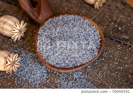 Poppy seeds and dried poppy heads on a table 70048591